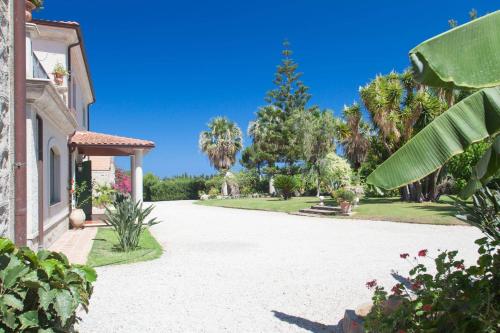 a driveway with palm trees and a house at Rosmarino Park in SantʼAgata di Militello