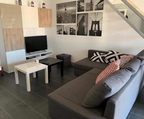 sala de estar con sofá y TV en Port Brescou, T3 en duplex climatisé, superbe vue sur le port, en Cap d'Agde