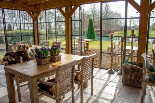 un ampio giardino d'inverno con tavolo e sedie in legno di Landhuis Hotel de Hilkensberg a Broekhuizen