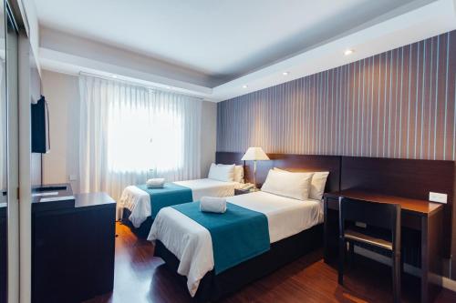 a hotel room with two beds and a desk at Dorá Hotel Buenos Aires in Buenos Aires