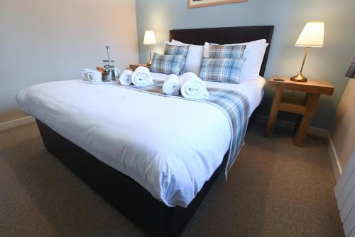 a bedroom with a large white bed with towels on it at Birchbrae Highland Lodges in Onich