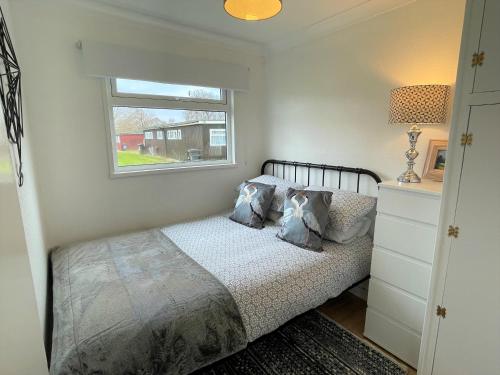 a bedroom with a bed and a window at 93 Broadside Holiday Chalet near Broads & Beaches in Stalham