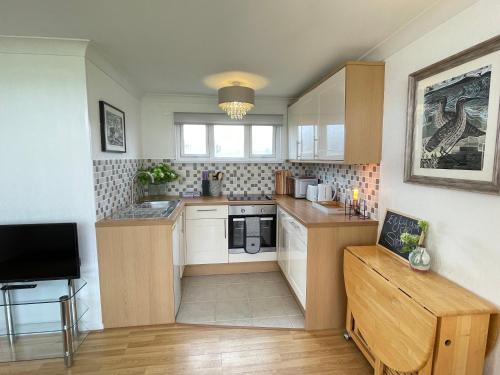 a small kitchen with white cabinets and a table at 93 Broadside Holiday Chalet near Broads & Beaches in Stalham