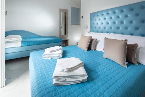 sypialnia z niebieskim łóżkiem i ręcznikami w obiekcie Hotel Italia w Rimini