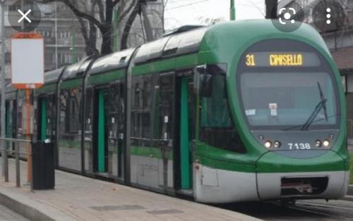 a green and white tram on a city street at Dolce Riposo in Cinisello Balsamo