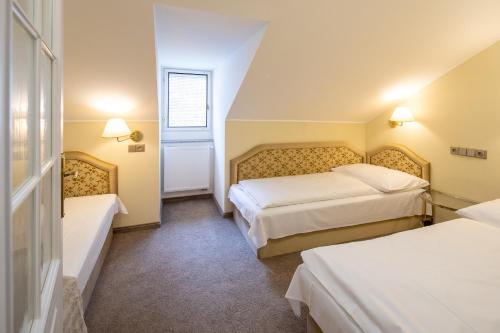 a hotel room with two beds and a window at Villa Basileia Riverside in Karlovy Vary