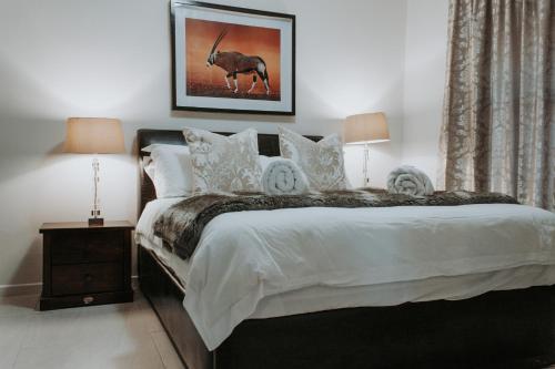 a bedroom with a bed with white sheets and a antelope at Bloemendal Wine Estate Accommodation in Cape Town