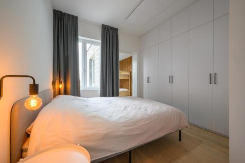 a white bedroom with a bed and a window at Gezellig appartement op 100m van zee te Middelkerke in Middelkerke