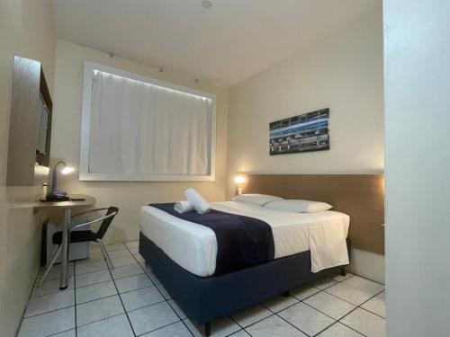 Habitación de hotel con cama, mesa y escritorio. en Hotel de Carvalho en Florianópolis