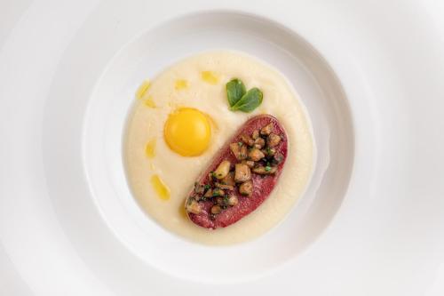 a plate of food with an egg and a piece of meat at Villa Basileia Riverside in Karlovy Vary
