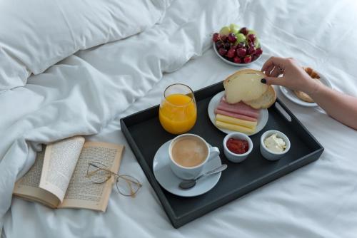 a tray of breakfast food on a bed with a book at Portal Plaza Suites in Mendoza