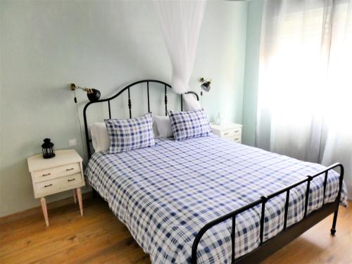 - une chambre avec un lit doté d'une couverture en damier et d'une fenêtre dans l'établissement Logrocity Puerta del Ebro Parking privado gratis, à Logroño