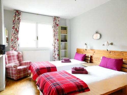 a bedroom with two beds and a chair at Logrocity Puerta del Ebro Parking privado gratis in Logroño