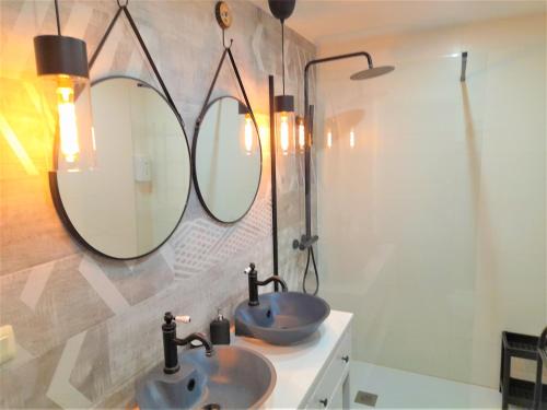 a bathroom with two sinks and two mirrors at Logrocity Puerta del Ebro PARKING PRIVADO GRATIS in Logroño