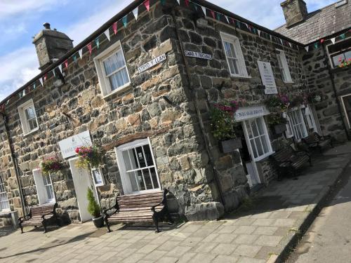 a stone building with two benches in front of it at Flat 2 - Y Sgwar Restaurant in Morfa Bychan