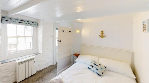 a small bedroom with a bed and a window at Lobster Cove, 50 yards from the sea in Port Isaac