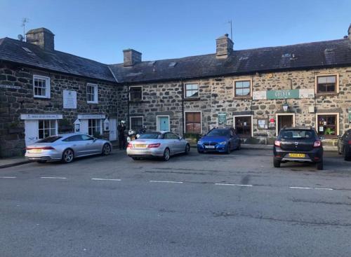 a group of cars parked in front of a stone building at Flat 2 - Y Sgwar Restaurant in Tremadoc