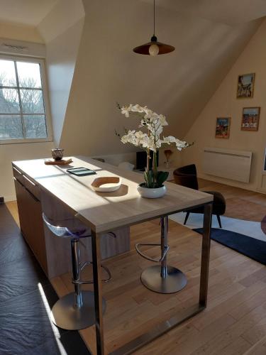 un îlot de cuisine avec une table avec des fleurs dessus dans l'établissement Le Victoria Baie de Somme, à Saint-Valery-sur-Somme