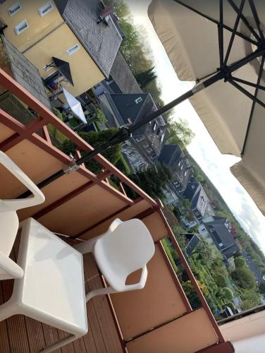 a balcony with white chairs and a view of a city at FEWO "Rabennest " Gemütliche Wohnung nahe Rabensteinklinikum - kein separates Schlafzimmer, Studiowohnung in Chemnitz