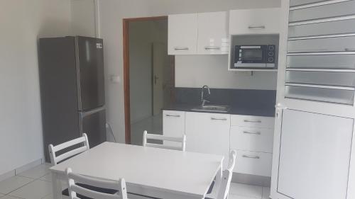 a kitchen with a white table and a refrigerator at T2 en résidence chez l'habitant in Ducos