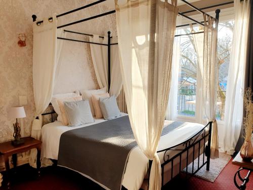 a bedroom with a canopy bed and a window at Hôtel Saint Cyr in La Ferté-Saint-Cyr