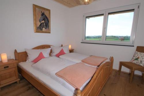 a bedroom with a bed with white sheets and pink pillows at Linda‘s Ferien-Pferdehof in Sigmarszell