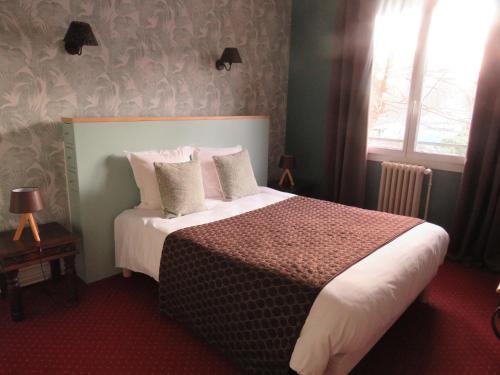 a bedroom with a large bed with white sheets and pillows at Logis Hôtel Saint Cyr in La Ferté-Saint-Cyr