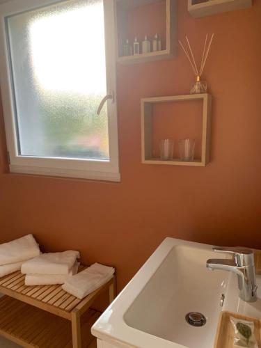 La salle de bains est pourvue d'un lavabo, d'une fenêtre et de serviettes. dans l'établissement Dom’s Garden, à Livarot
