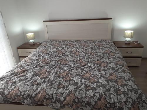 a bed in a bedroom with two night stands with lamps at Sara apartman in Livezeni