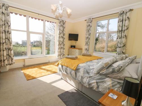 a bedroom with a bed and two large windows at Gwel Y Castell Castle View in Criccieth