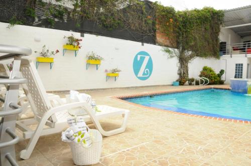 a swimming pool with two chairs next to a white wall at Zarabanda Campestre - Moderna Casa Campestre para alojamiento y eventos in Tuluá