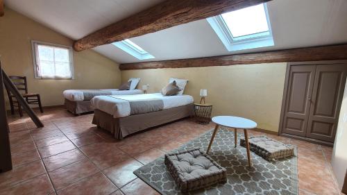 a bedroom with two beds and a table and windows at Logis Hôtel La Bastide Saint Bach in Suze-la-Rousse