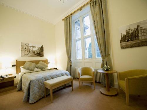 een slaapkamer met een bed, een raam en een stoel bij Stoke Rochford Hall in Grantham