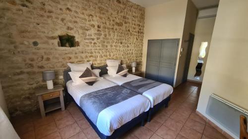 a bedroom with a bed and a brick wall at Logis Hôtel La Bastide Saint Bach in Suze-la-Rousse