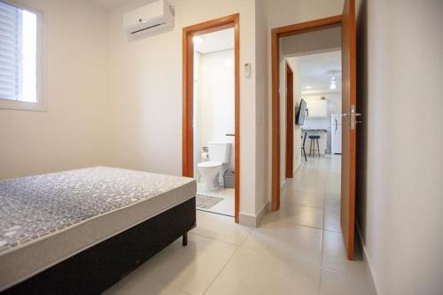 a bedroom with a bed and a bathroom with a toilet at Apto 2 Dorms, 1 Suíte, JP2 Home Resort Ubatuba - Churrasqueira Gourmet, Ar Condicionado, Piscinas, Sauna e Salão de Jogos in Ubatuba