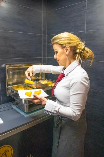 a woman holding a plate of food in front of a counter at Hotel Capital with private wellness in Nitra