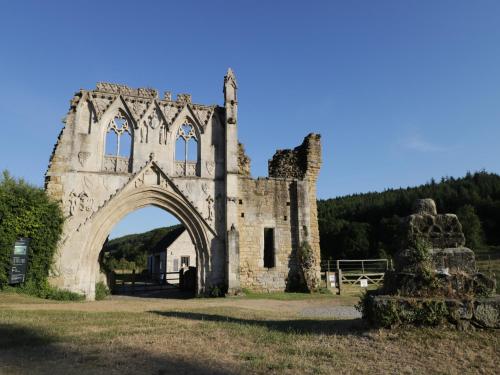 an old stone building with an arch in a field at Chalet 3 in Ganton