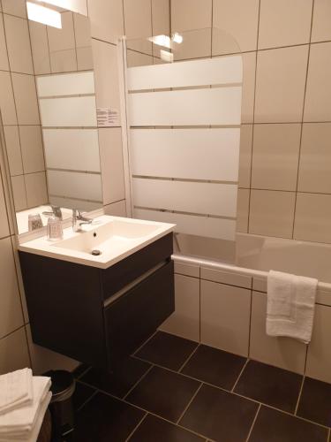 ein Badezimmer mit einem Waschbecken, einer Badewanne und einem Spiegel in der Unterkunft Hôtel Saint Cyr in La Ferté-Saint-Cyr