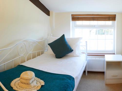 a bedroom with a bed with a straw hat on it at Courtyard Cottage in Filey
