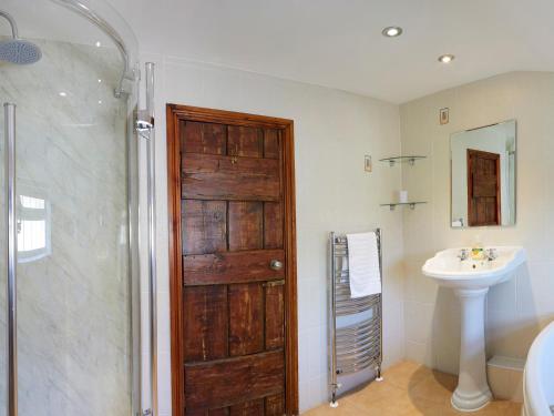 a bathroom with a wooden door and a sink at Courtyard Cottage in Filey