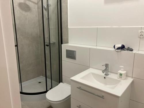 a bathroom with a shower and a toilet and a sink at Apartament Centrum Szczytno I in Szczytno