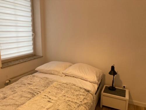 a bedroom with a bed and a lamp on a night stand at Apartament Centrum Szczytno I in Szczytno