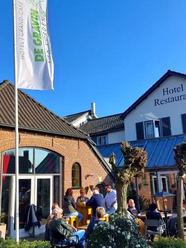 a group of people sitting at tables outside a hotel restaurant at Hotel De Gravin van Vorden in Vorden