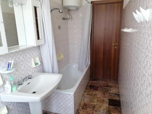 uma casa de banho com um lavatório, uma banheira e um espelho. em Appartamento con Giardino em Levanto