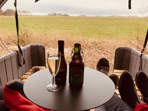 a table with a bottle of champagne and a glass at Hof Steinhütten Schlafstrandkorb in Westerhever