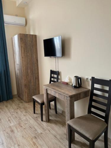 Zimmer mit einem Tisch, 2 Stühlen und einem TV in der Unterkunft Glendale Boutique Hotel in Yerevan