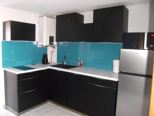 - une cuisine avec des placards noirs et bleus et un réfrigérateur dans l'établissement Appartement Cap d'adge à côté camp natu, au Cap d'Agde