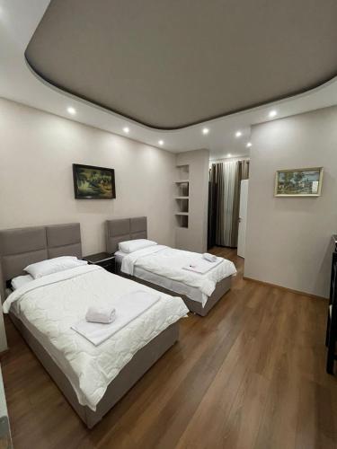 two beds in a hotel room with wooden floors at Hotel Holiday in Koplik