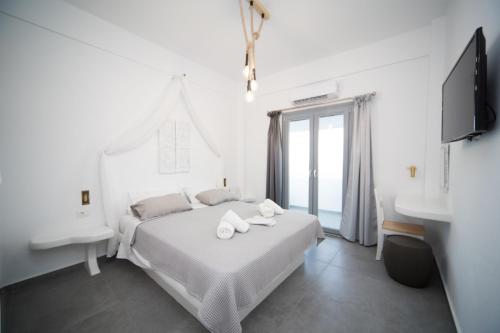 a white bedroom with a bed and a sink at Eunoia Apartments in Fira