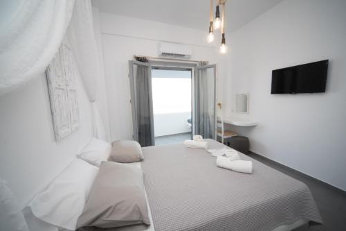 a white bedroom with a bed and a window at Eunoia Apartments in Fira